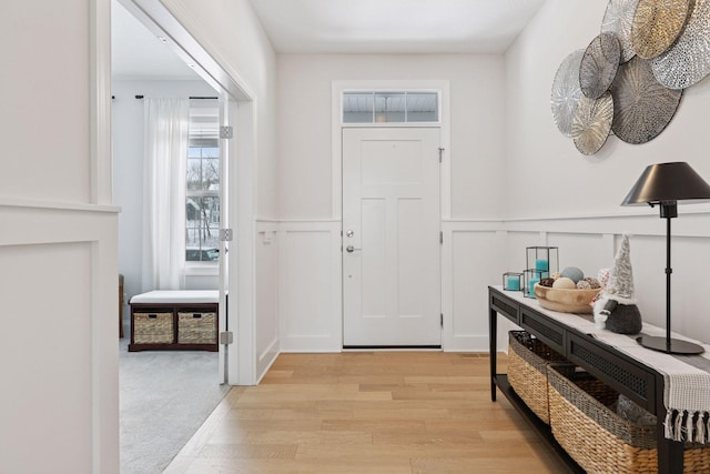 entryway featuring a wainscoted wall, light wood-style floors, and a decorative wall