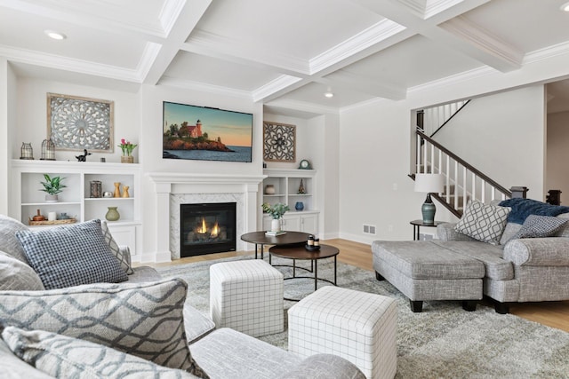 living area featuring a high end fireplace, visible vents, stairway, beamed ceiling, and light wood-type flooring