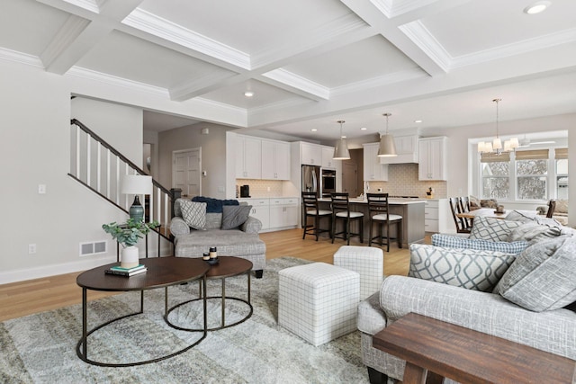 living room with beam ceiling, a notable chandelier, visible vents, and light wood finished floors