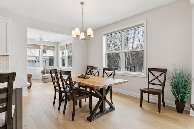 dining space with light wood-type flooring, baseboards, and a chandelier