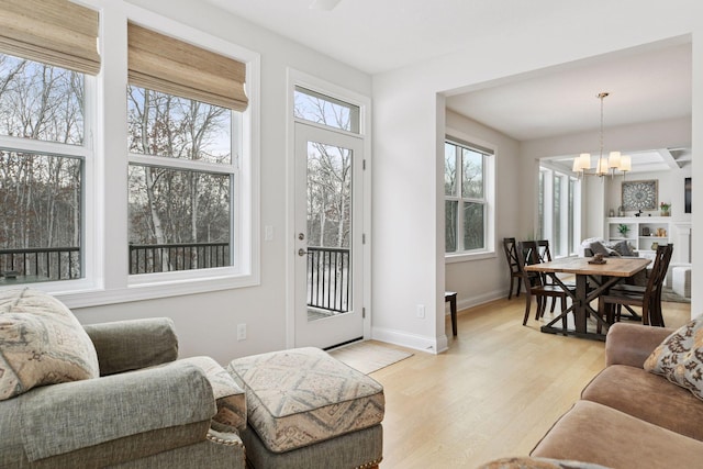 living room featuring a notable chandelier, light wood-style floors, and baseboards