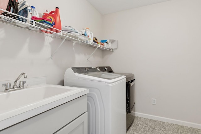 laundry area featuring a sink, baseboards, separate washer and dryer, and laundry area