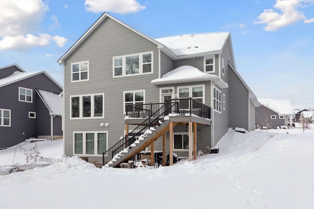 snow covered property with stairs and a wooden deck