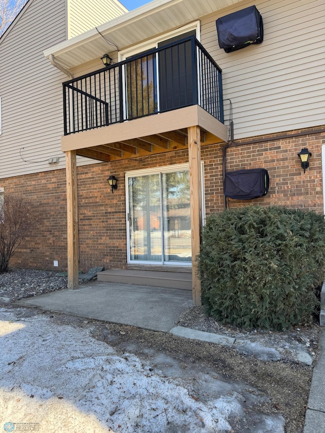 entrance to property featuring a balcony and brick siding