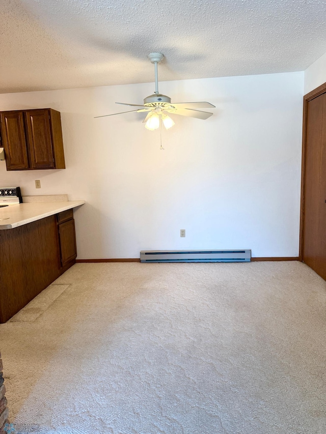 kitchen with a baseboard heating unit, light countertops, a textured ceiling, and light colored carpet