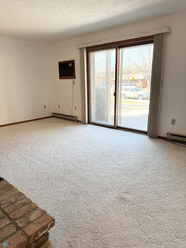 carpeted spare room with a wall unit AC, baseboards, a baseboard heating unit, and a textured ceiling