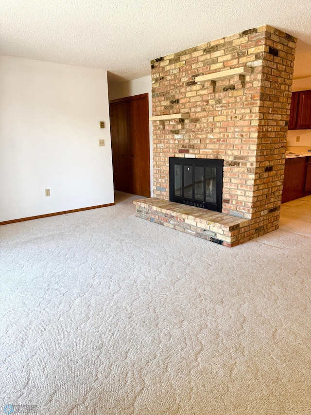 unfurnished living room featuring a textured ceiling, carpet floors, a brick fireplace, and baseboards