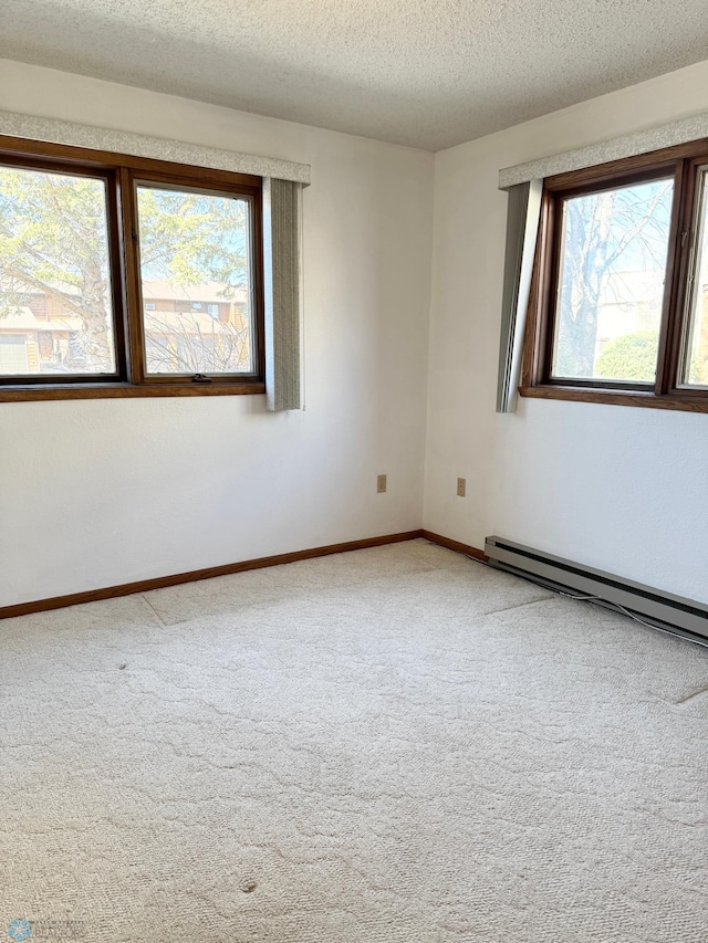 spare room with carpet floors, baseboard heating, a wealth of natural light, and baseboards