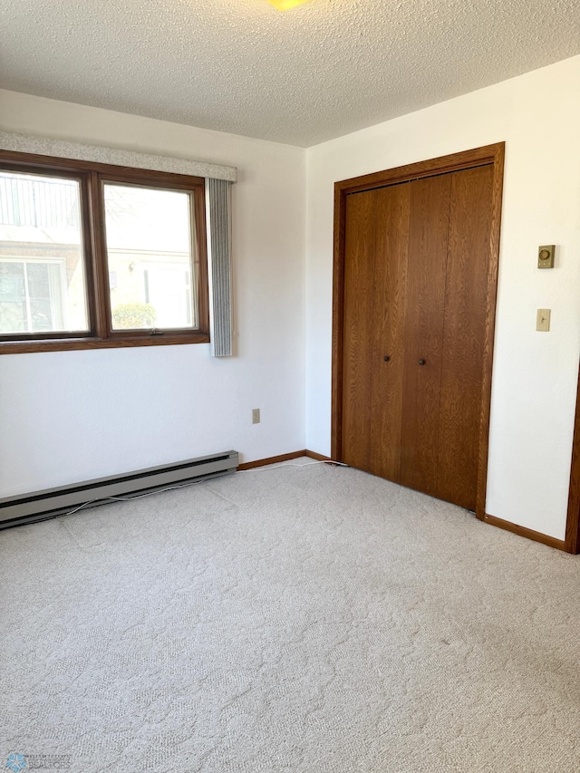 unfurnished bedroom featuring carpet floors, baseboard heating, a closet, and baseboards