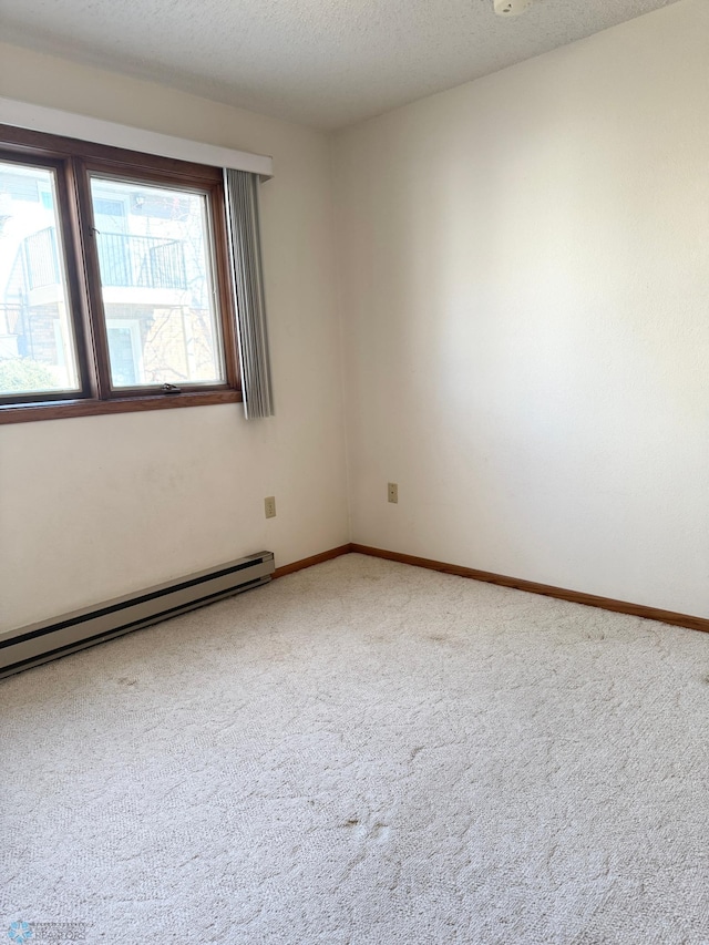 empty room with baseboards, a baseboard heating unit, a textured ceiling, and carpet flooring