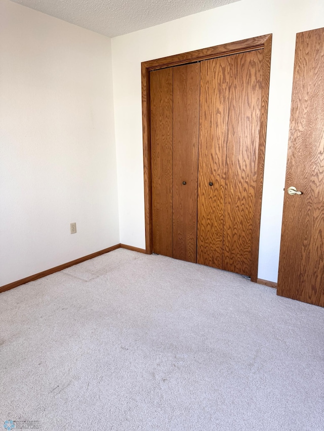 unfurnished bedroom featuring carpet, a textured ceiling, and baseboards