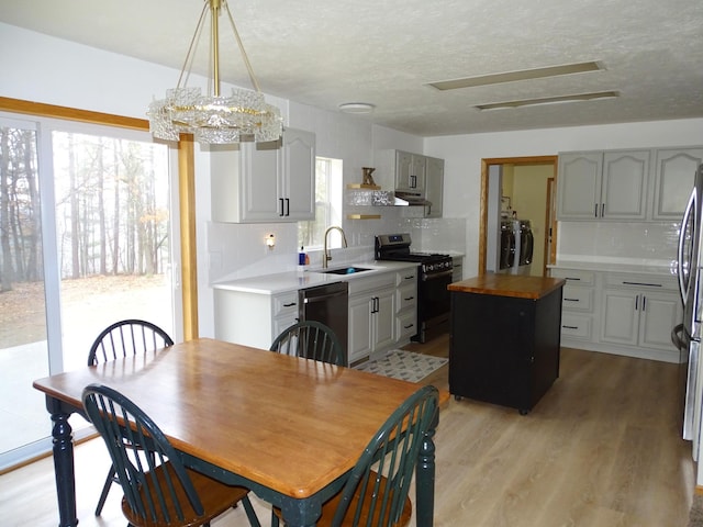 dining room with a textured ceiling, separate washer and dryer, and light wood finished floors