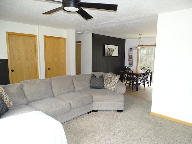 carpeted living area featuring a textured ceiling, ceiling fan, and baseboards