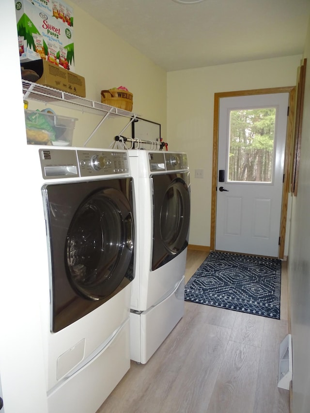 laundry area with light wood-style floors, laundry area, and washer and clothes dryer