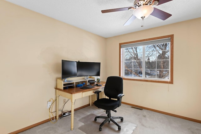 carpeted office featuring a ceiling fan, visible vents, a textured ceiling, and baseboards