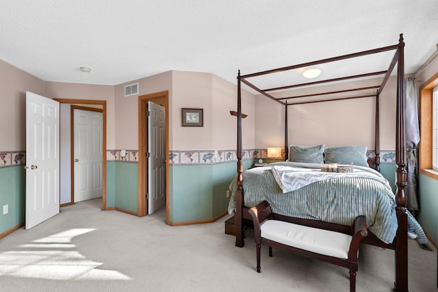 bedroom with a textured ceiling, carpet floors, visible vents, and baseboards