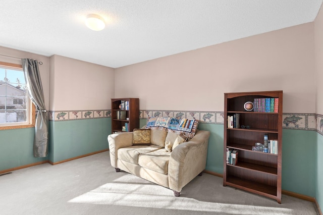 living area with carpet floors, a textured ceiling, and baseboards