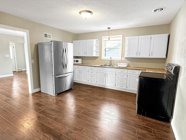 312 4th St E, Jasper, MN 56144 - kitchen featuring freestanding refrigerator, a sink, a textured ceiling, white microwave, and dark wood-type flooring