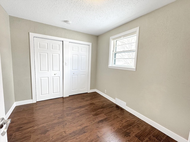 312 4th St E, Jasper, MN 56144 - unfurnished bedroom with dark wood-style floors, a closet, baseboards, and a textured ceiling