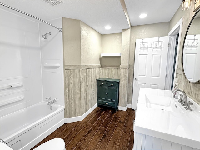 312 4th St E, Jasper, MN 56144 - bathroom featuring wood finished floors, shower / bathtub combination, vanity, a wainscoted wall, and toilet