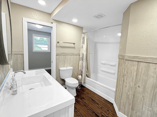 312 4th St E, Jasper, MN 56144 - full bath featuring wainscoting, toilet, wood finished floors, a textured wall, and shower / bath combo with shower curtain