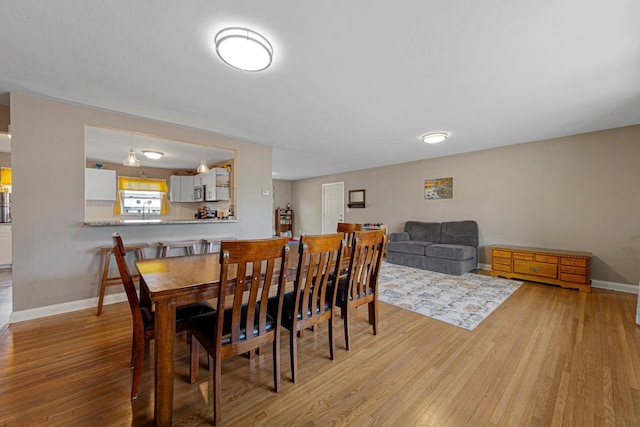 dining space featuring baseboards and light wood finished floors