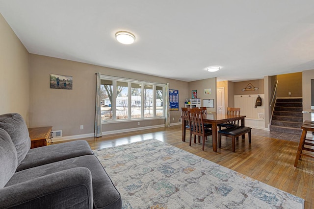 dining area with baseboards, stairs, visible vents, and wood finished floors