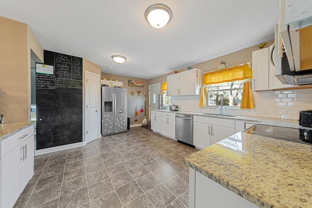 kitchen with a sink, baseboards, white cabinets, appliances with stainless steel finishes, and decorative backsplash