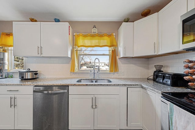 kitchen with decorative backsplash, appliances with stainless steel finishes, white cabinets, and a sink