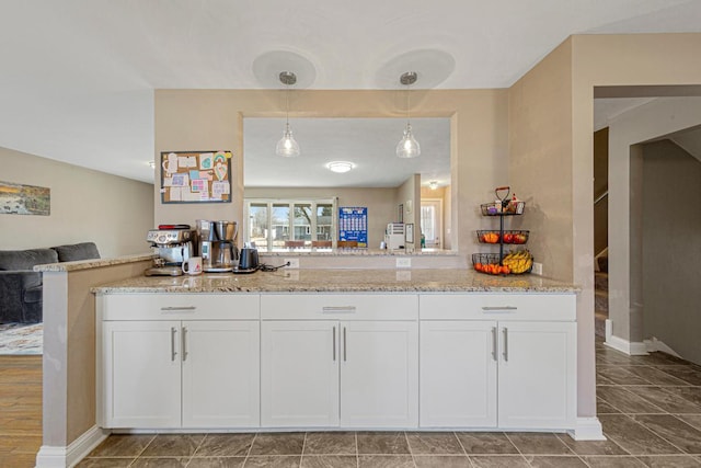 kitchen with pendant lighting, open floor plan, white cabinets, and light stone countertops