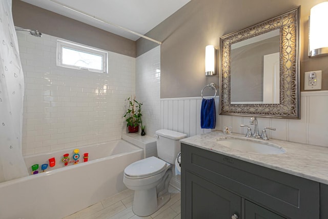 bathroom featuring shower / bath combination with curtain, wainscoting, vanity, and toilet