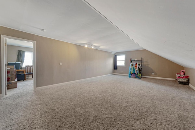 interior space featuring carpet, vaulted ceiling, and baseboards