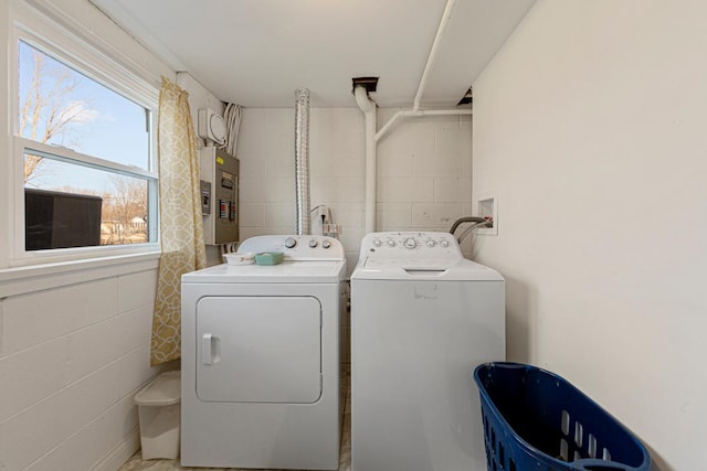 laundry area featuring laundry area, washing machine and clothes dryer, electric panel, and concrete block wall