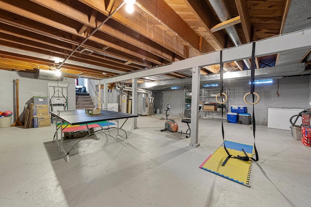 unfinished basement featuring stairs and water heater