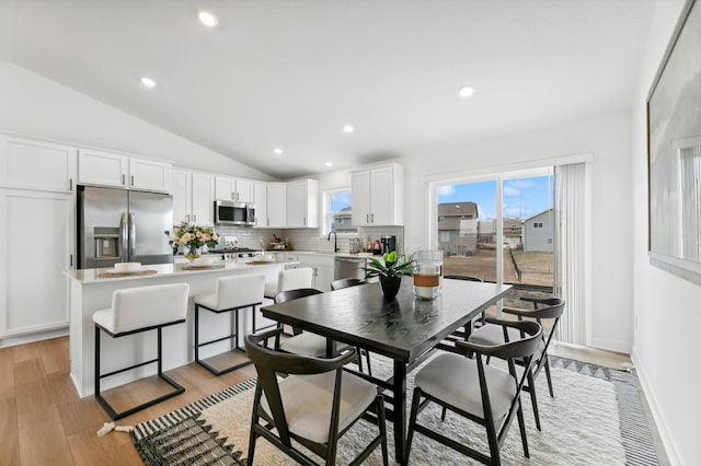 dining space featuring vaulted ceiling, light wood-style flooring, recessed lighting, and baseboards