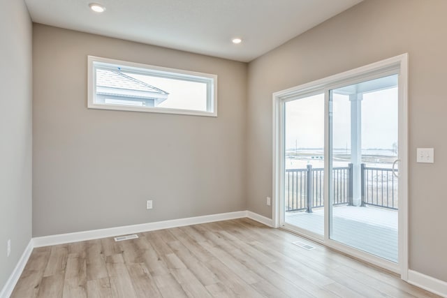 spare room featuring visible vents, light wood-style floors, and baseboards