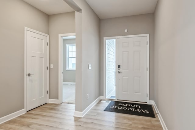 foyer entrance with light wood-style flooring and baseboards