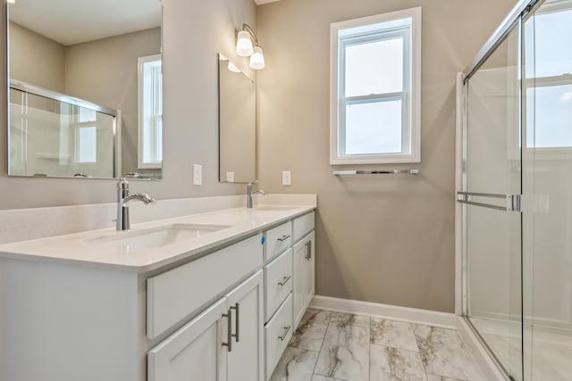 bathroom with a wealth of natural light, marble finish floor, a shower stall, and a sink