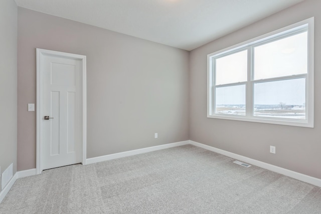 carpeted spare room with visible vents and baseboards