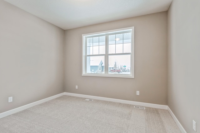 empty room with visible vents, carpet floors, and baseboards