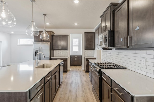 kitchen with a sink, dark brown cabinets, light wood finished floors, and stainless steel appliances