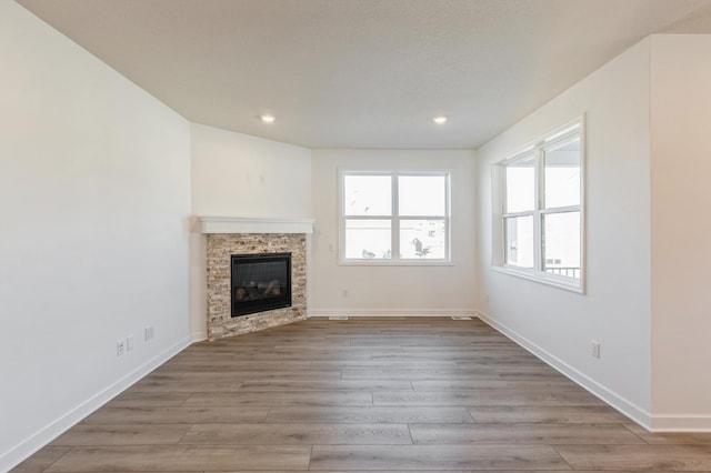 unfurnished living room featuring a glass covered fireplace, recessed lighting, baseboards, and wood finished floors