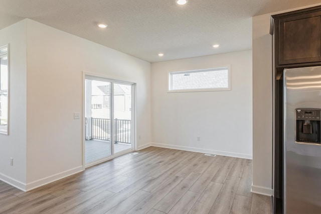 interior space with recessed lighting, baseboards, light wood finished floors, and a textured ceiling