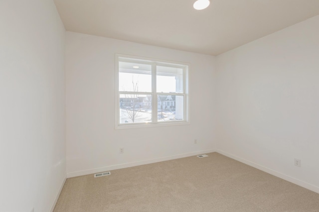 empty room featuring baseboards, visible vents, and light carpet