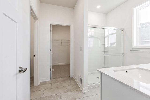 bathroom featuring a walk in closet, tile patterned floors, visible vents, and a stall shower