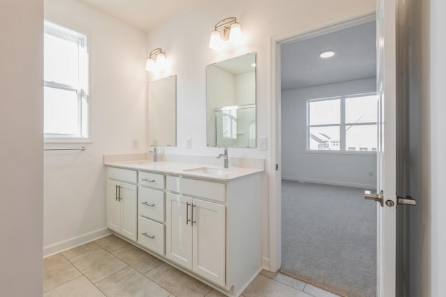 full bath with a wealth of natural light, tile patterned flooring, double vanity, and a sink