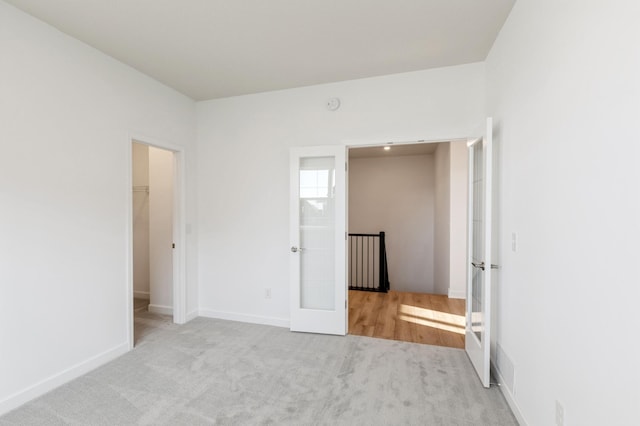 unfurnished bedroom featuring french doors, carpet floors, baseboards, and a spacious closet