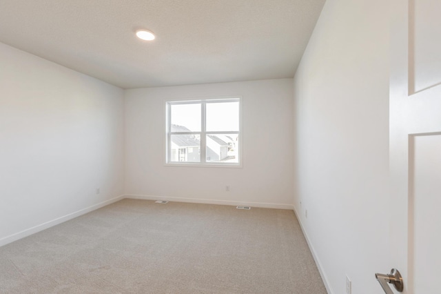 empty room featuring baseboards and light colored carpet