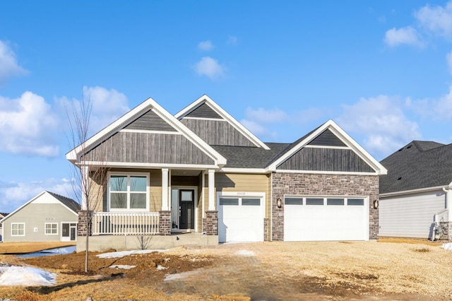 craftsman-style home with covered porch, driveway, a shingled roof, and a garage