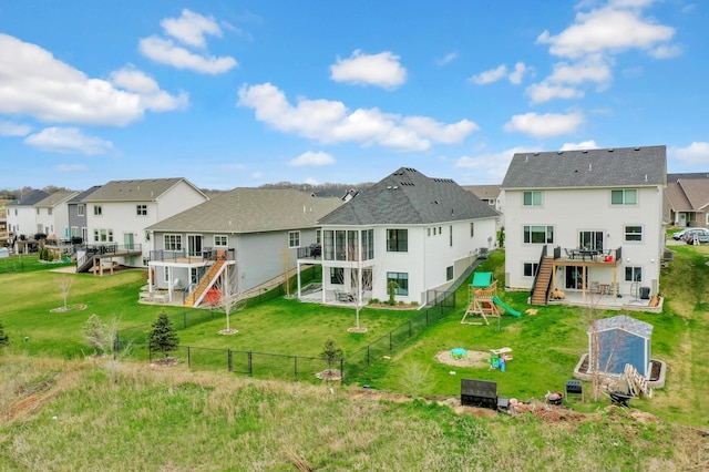 back of house featuring a playground, a lawn, a wooden deck, a residential view, and a patio area